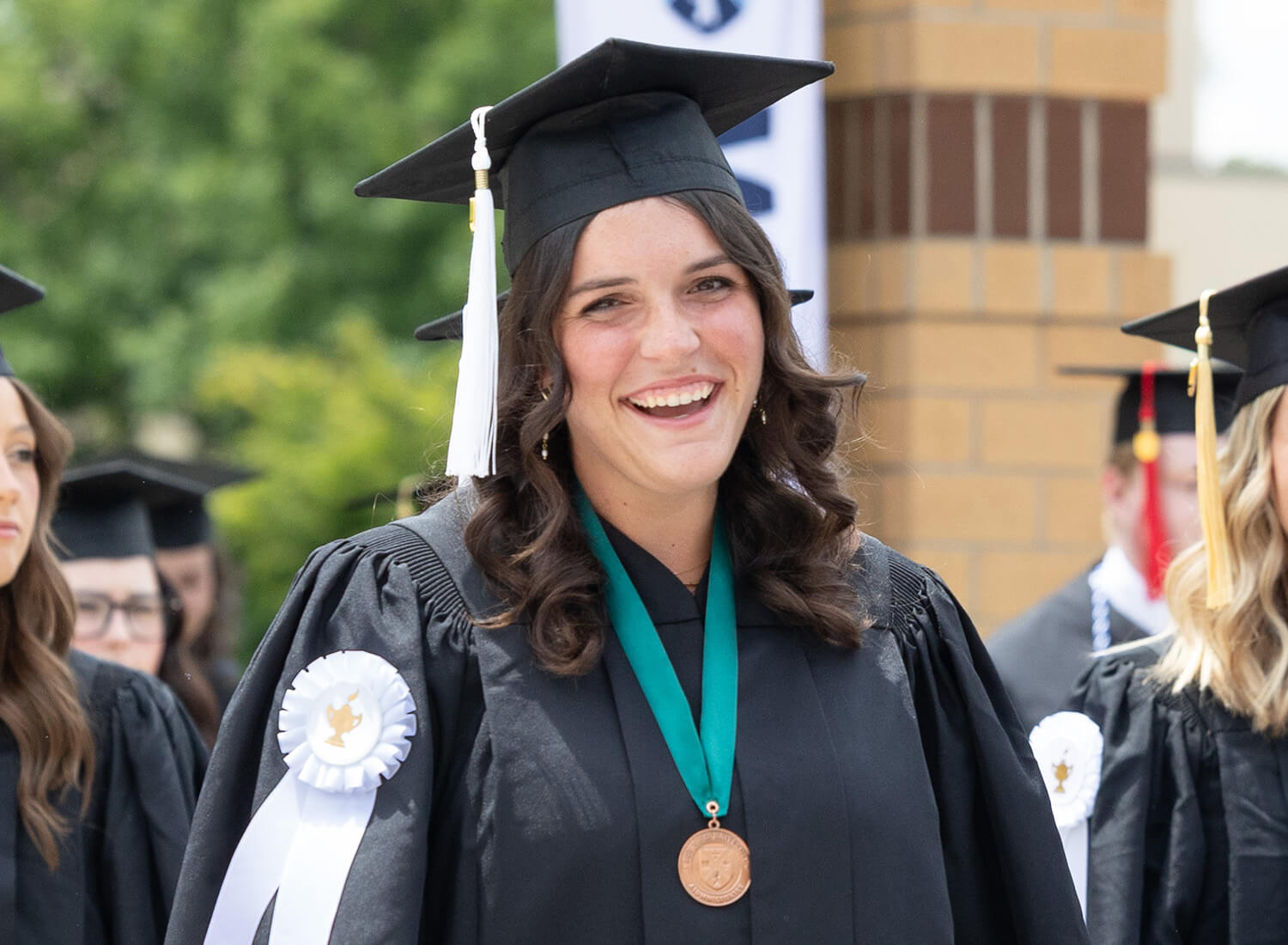 A smiling BJU graduate wearing a medal at commencement