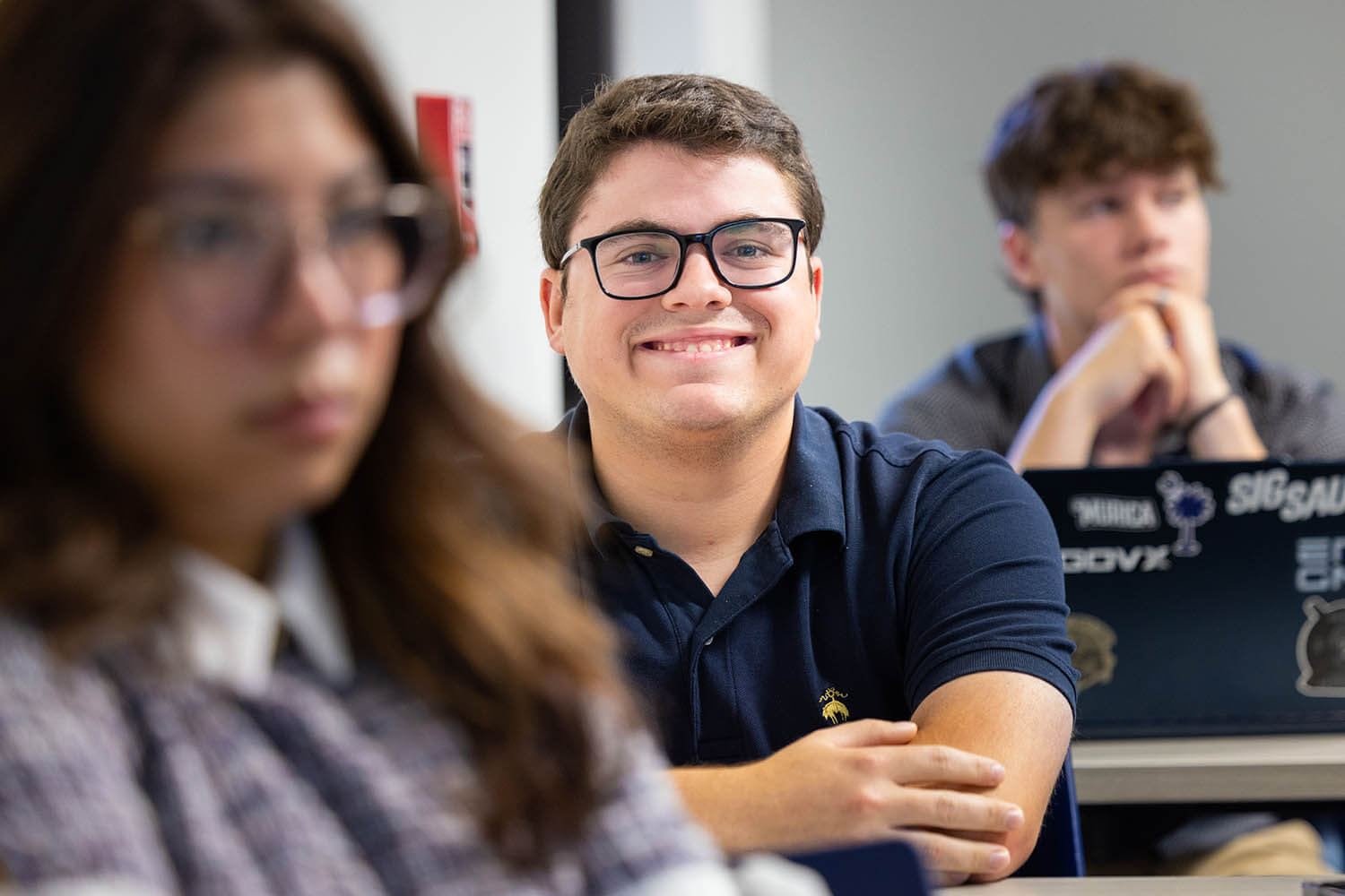 A smiling BJU student in class with classmates nearby